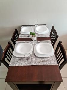 a wooden table with plates and glasses on it at Acogedor Departamento centrico in Cochabamba