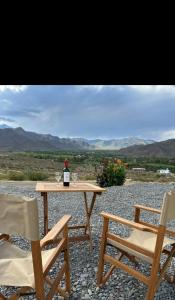 uma mesa com uma garrafa de vinho e duas cadeiras em Cabaña Abra Del Monte em Cachí