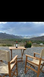 a table with a bottle of wine and two chairs at Cabaña Abra Del Monte in Cachí