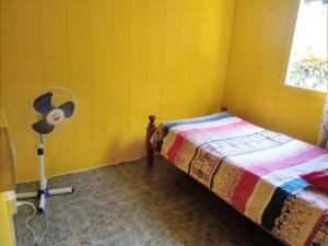 a yellow room with a bed and a fan at Ian Creole Garaden Cottages in Roseau