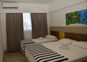 a hotel room with two beds and a window at Flat no Olimpia Park Resort (ao lado do Thermas dos Laranjais) in Olímpia