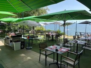 un restaurante con mesas, sillas y sombrillas en Hôtel de la Plage à Gland, en Gland