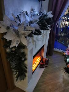 a fireplace with a christmas wreath and a christmas tree at Apartman sa ljuljaskom in Zlatibor