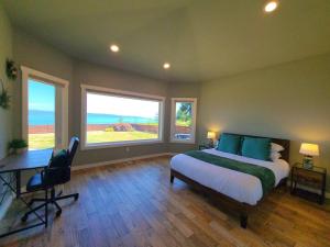 a bedroom with a bed and a desk and two windows at New Lighthouse Port Susan View House Camano in Bretland