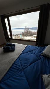 Bett in einem Zimmer mit einem großen Fenster in der Unterkunft Casa Los Ñires Ushuaia in Ushuaia