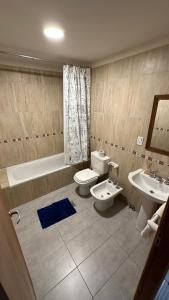 a bathroom with two sinks and a toilet and a bath tub at Casa Los Ñires Ushuaia in Ushuaia