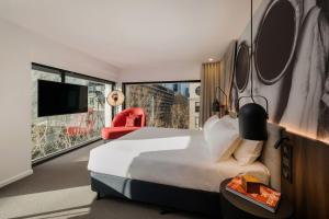 a hotel room with a bed and a large window at Hotel Indigo Melbourne on Flinders by IHG in Melbourne