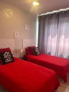 um quarto com 2 camas com lençóis vermelhos e uma janela em First line, upscale apartment Los Cristianos! Free parking em Arona