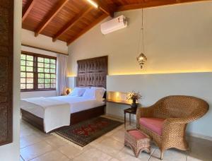 a bedroom with a large bed and a chair at Casa de Novela in Pirenópolis