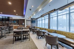 a restaurant with tables and chairs and windows at SpringHill Suites by Marriott Detroit Sterling Heights in Sterling Heights