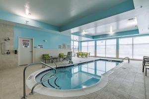 een zwembad in een gebouw met stoelen en tafels bij SpringHill Suites by Marriott Detroit Sterling Heights in Sterling Heights