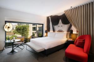 um quarto com uma cama e uma cadeira vermelha em Hotel Indigo Melbourne on Flinders, an IHG Hotel em Melbourne