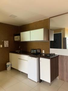 une cuisine avec des placards blancs et un comptoir dans l'établissement Iracema Residence Flat - Apto Particular, à Fortaleza