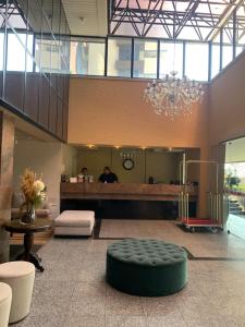a large lobby with a circular green ottoman in the middle at Iracema Residence Flat - Apto Particular in Fortaleza