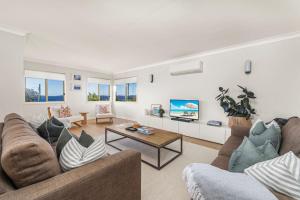 een woonkamer met 2 banken en een tv bij On Cyrus at Hyams Beach in Hyams Beach