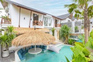 uma villa com uma piscina e um guarda-sol de palha em Villa Asri Canggu 3br, Poolside sofa & bar area em Canggu