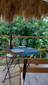 una mesa con copas de vino y una sombrilla de paja en Quédate Aquí en Las Galeras