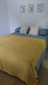 Una cama con una manta amarilla encima. en Quédate Aquí en Las Galeras