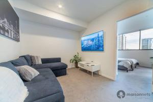 sala de estar con sofá azul y dormitorio en Mod Brisbane Apt near Southbank W Pool & Parking, en Brisbane