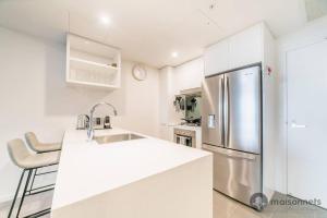 - une cuisine blanche avec un réfrigérateur en acier inoxydable dans l'établissement Mod Brisbane Apt near Southbank W Pool & Parking, à Brisbane