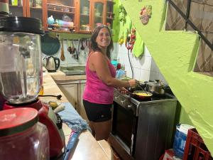 una mujer parada en una cocina preparando comida en una estufa en Casa Hogar Martita, en Puerto Baquerizo Moreno