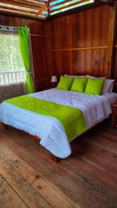 1 dormitorio con 1 cama grande con almohadas verdes en Mama Yeya raíces, en San Cipriano