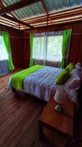 Un dormitorio con una cama con sábanas verdes y una mesa. en Mama Yeya raíces, en San Cipriano