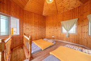 濟州的住宿－Love Pension，配有木墙和窗户的客房内的两张床