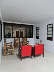 een woonkamer met rode stoelen en een tafel bij MoRue's Den in Mabini