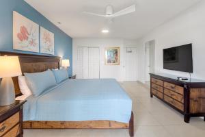 a bedroom with a blue bed and a television at Caribbean Oasis on Sunset Beach in Maho Reef