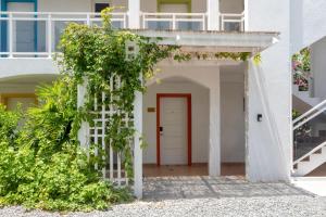 a white house with a red door and plants at Maho Beach House - Spacious 1 Bedroom Suite in Maho Reef