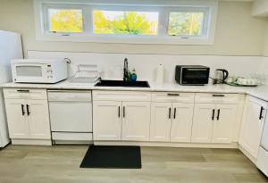 a kitchen with white cabinets and a sink and a microwave at VJ Home in Toronto