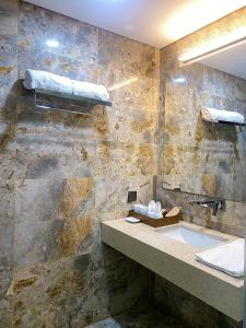 baño con lavabo y pared de piedra en Suha Villa- Flamingo Dai Lai Resort, en Phúc Yên