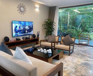 a living room with a couch and a tv at TD Villa- Dai Lai Resort in Phúc Yên