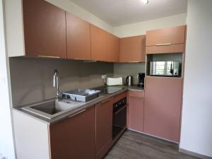 cocina con armarios marrones y fregadero en Appartement Bagnères-de-Luchon, 2 pièces, 6 personnes - FR-1-313-226, en Luchon