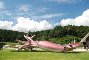 a giant squid statue sitting in the grass at Town Hotel 41 in Kanazawa