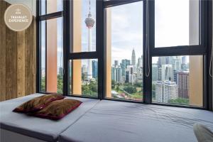 een bed met 2 kussens voor een groot raam bij Ceylonz Suite KLCC, Travelet in Kuala Lumpur