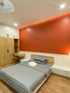 een slaapkamer met een bed met een oranje muur bij Happy Hotel Bình Tân in Ho Chi Minh-stad