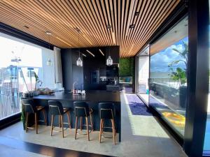 una cocina con una gran isla negra con taburetes de bar en Entertainers penthouse with 5 bedrooms pool & spa en Auckland