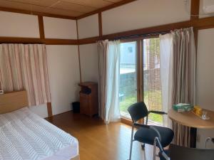um quarto com uma cama, uma secretária e uma janela em 民泊　筑紫野 em Chikushino