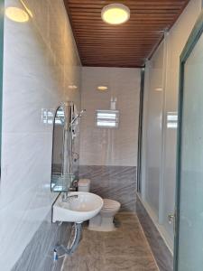 La salle de bains est pourvue d'un lavabo blanc et de toilettes. dans l'établissement Windy Home, à Ấp Man Ling