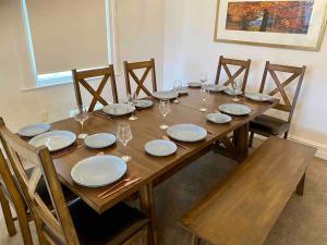 a wooden table with plates and wine glasses on it at Grand villa plus studio in central location in Auckland