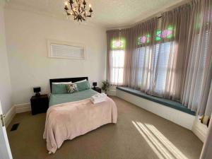 a bedroom with a bed with a pink blanket and windows at Grand villa plus studio in central location in Auckland