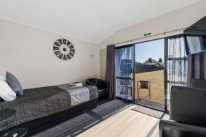 Central Inn Taupo في تاوبو: غرفة نوم بسرير وباب زجاجي منزلق