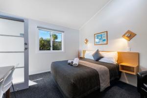 Central Inn Taupo في تاوبو: غرفة نوم مع سرير مع مكتب ونافذة