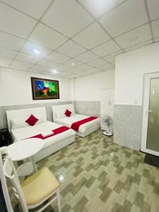 a room with two beds and a table and a tv at Vĩnh Phú Gia Hotel in Ho Chi Minh City