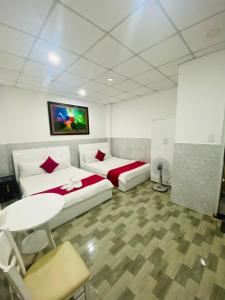 a room with two beds and a table and a tv at Vĩnh Phú Gia Hotel in Ho Chi Minh City