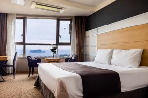 a hotel room with a bed and a desk and a window at Eastern Hotel Jeju in Seogwipo