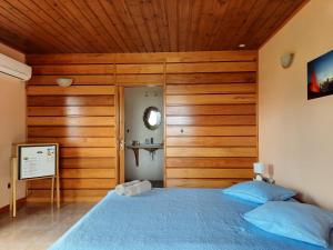 a bedroom with a blue bed and wooden walls at Ferme auberge le Ti'planteur in Saint-Philippe
