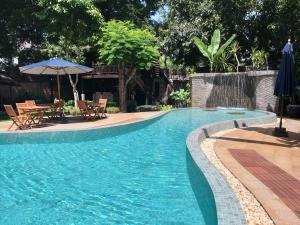 a swimming pool with chairs and an umbrella at VILLA MASSILIA in Siem Reap